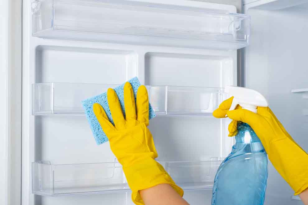 limpeza da geladeira e freezer pessoa usando luvas de borracha amarela para limpeza com um pano umido enquanto limpa a geladeira