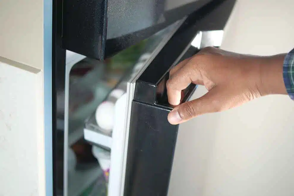pessoa abrindo geladeira preta