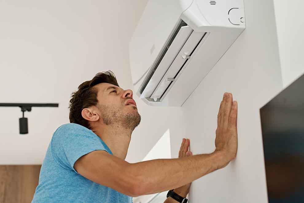 cheiro de mofo homem vendo o ar condicionado com cheiro ruim de mofo de uma sala de estar em um dia ensolarado