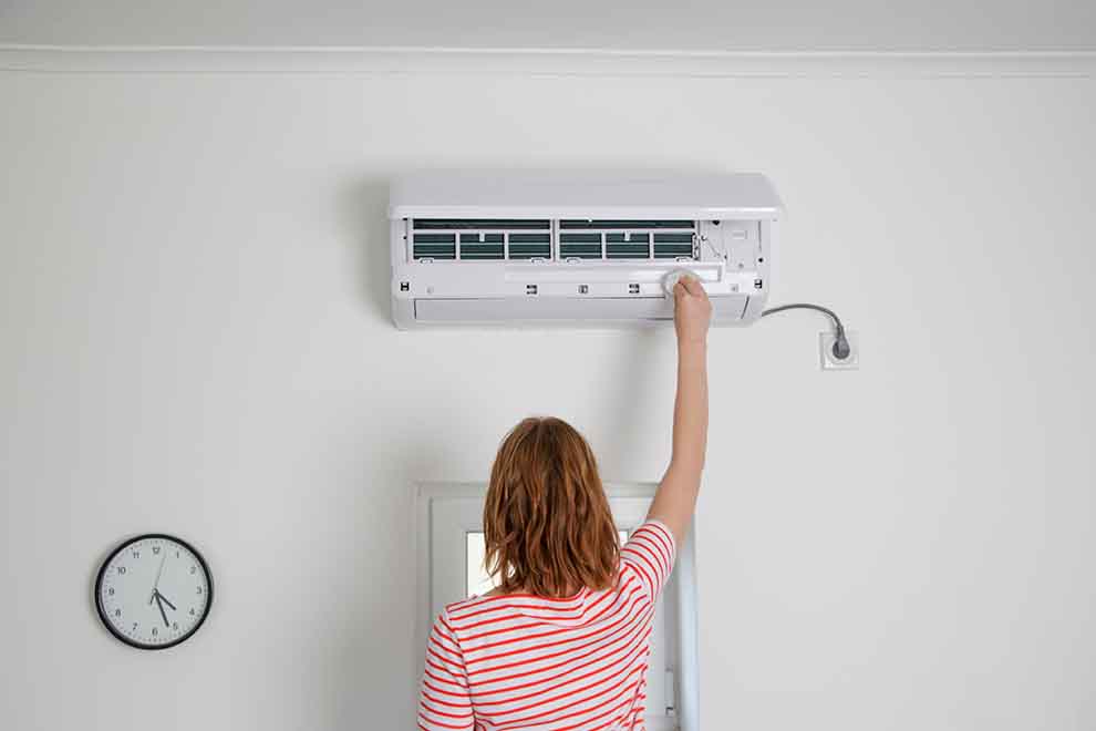 mulher de blusa rosa mexendo em ar condicionado