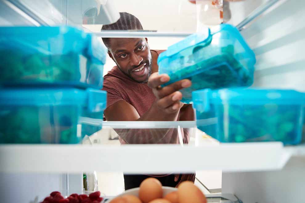 Homem organizando alimentos em geladeira