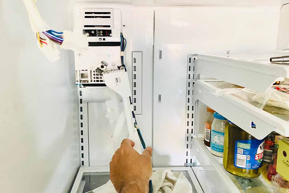 Pessoa consertando geladeira dentro da parte interna