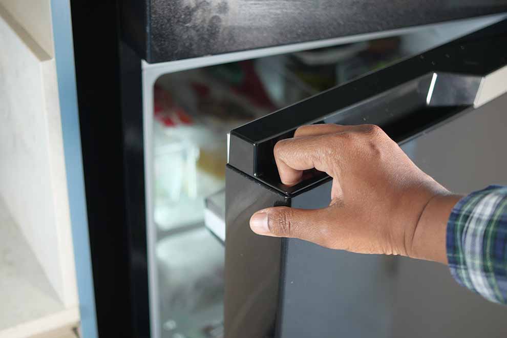Pessoa abrindo a porta de uma geladeira