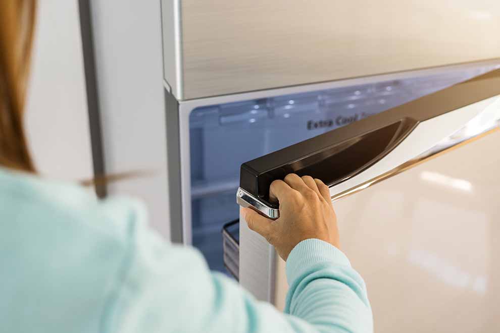 Pessoa abrindo a porta de um refrigerador moderno.